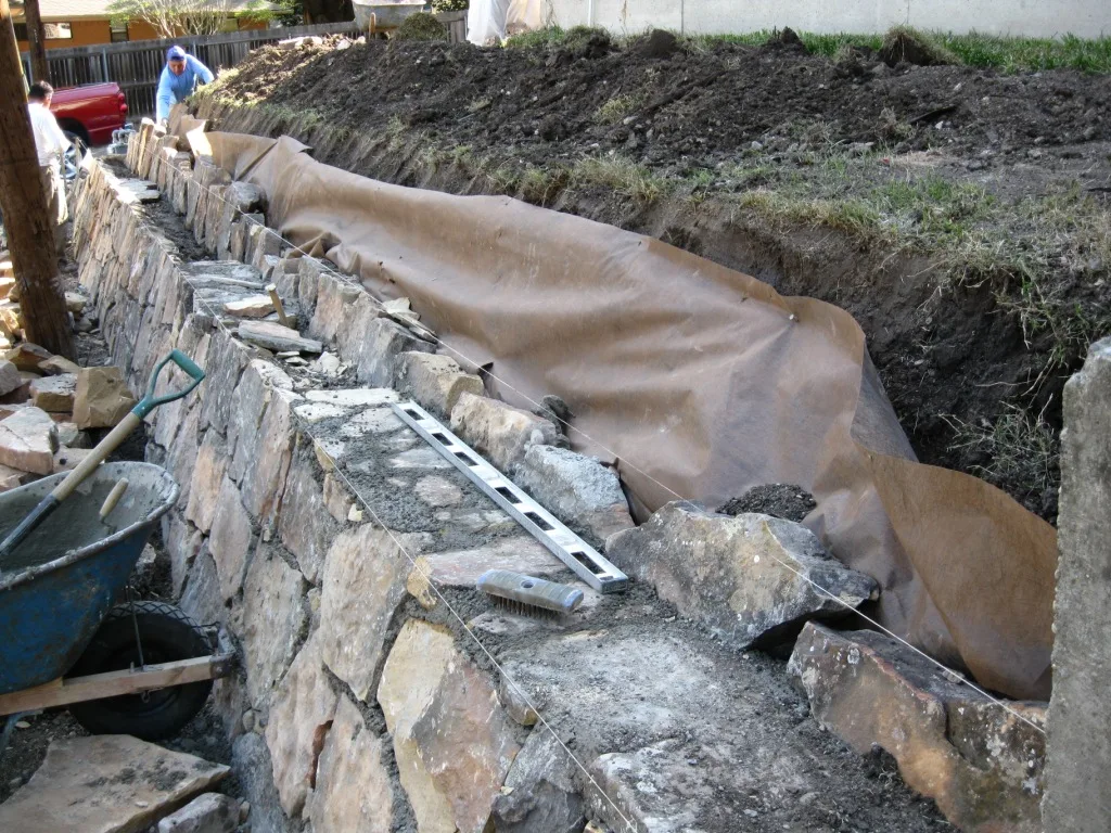 Armour stone retaining wall showing outward rotation on a Bracebridge Shield-slope property.