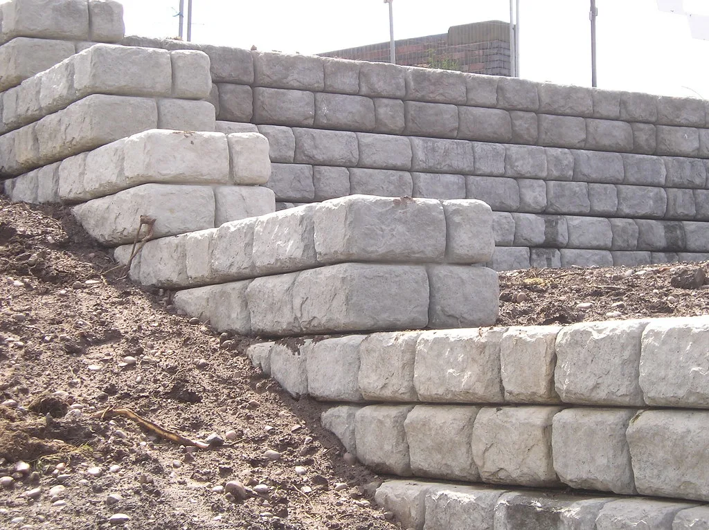Concrete block retaining wall showing mid-wall bulging on a steep Huntsville lot.