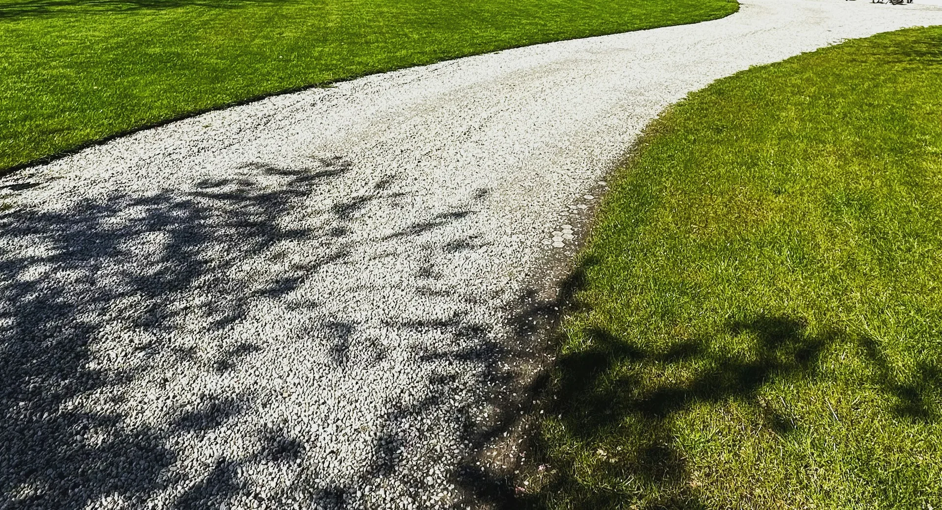 Freshly graded gravel driveway curving through a lawn